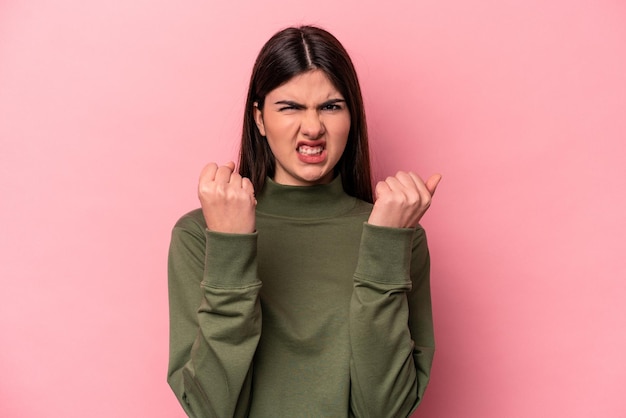 Joven mujer caucásica aislada de fondo rosa molesta gritando con las manos tensas