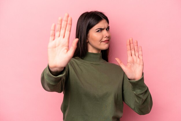 Joven mujer caucásica aislada de fondo rosa parada con la mano extendida mostrando la señal de stop que te impide