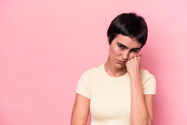 Joven mujer caucásica aislada de fondo rosa que se siente triste y pensativa, mirando el espacio de la copia.