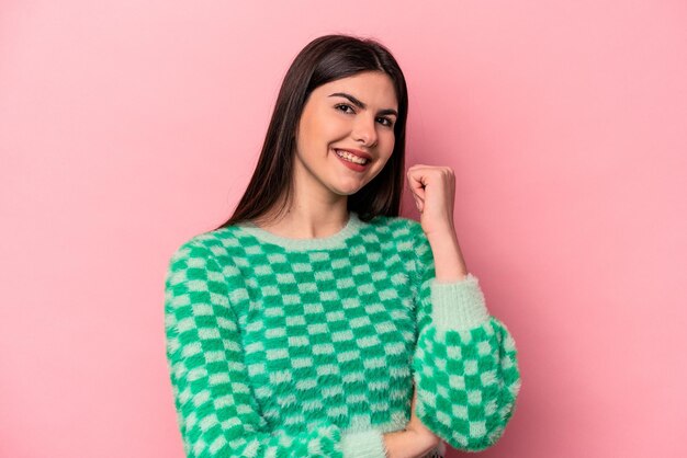 Joven mujer caucásica aislada de fondo rosa sonriendo feliz y confiada tocando la barbilla con la mano