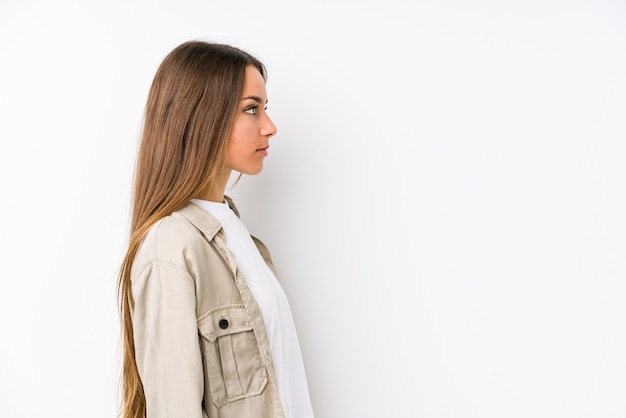 Joven mujer caucásica aislada mirando a la izquierda, pose de lado.