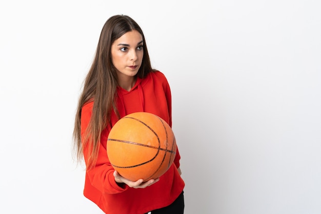 Joven mujer caucásica aislada en la pared blanca jugando baloncesto