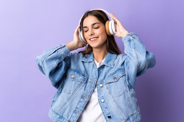 Joven mujer caucásica aislada en púrpura escuchando música