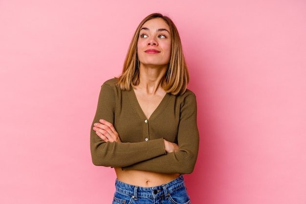 Joven mujer caucásica aislada en rosa soñando con lograr metas y propósitos