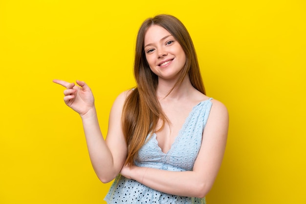 Joven mujer caucásica aislada sobre fondo amarillo dedo acusador hacia el lado