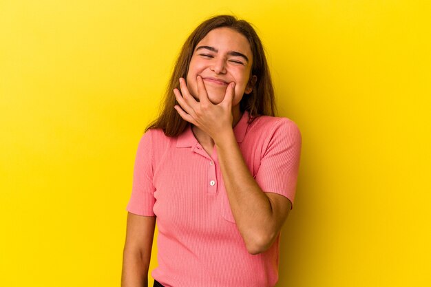 Joven mujer caucásica aislada sobre fondo amarillo dudando entre dos opciones.