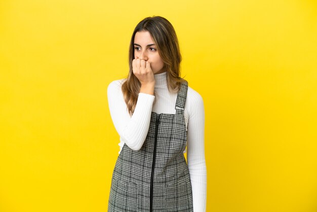 Joven mujer caucásica aislada sobre fondo amarillo con dudas