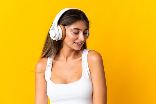 Joven mujer caucásica aislada sobre fondo amarillo escuchando música