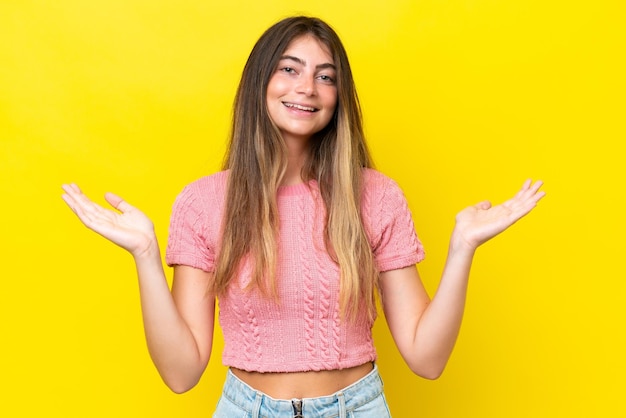 Joven mujer caucásica aislada sobre un fondo amarillo con expresión facial conmocionada