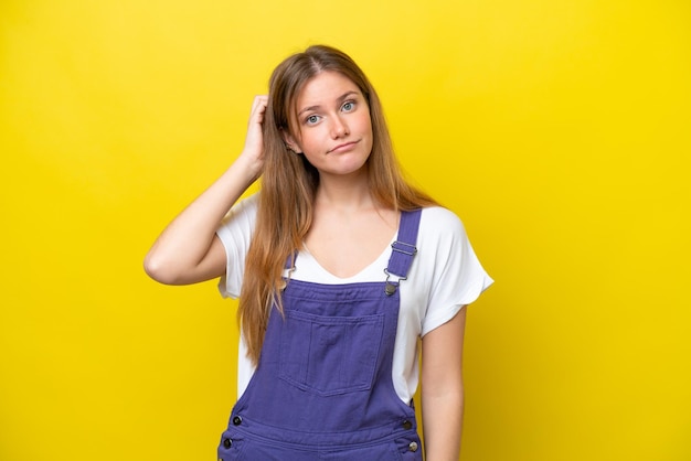 Joven mujer caucásica aislada sobre fondo amarillo con una expresión de frustración y no comprensión