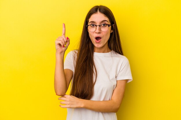 Joven mujer caucásica aislada sobre fondo amarillo con una gran idea, concepto de creatividad.