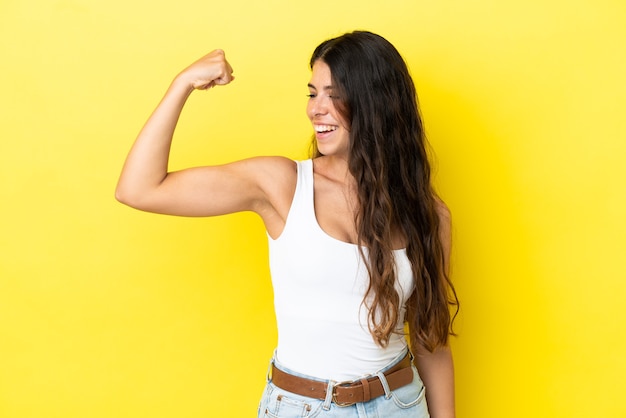 Foto joven mujer caucásica aislada sobre fondo amarillo haciendo gesto fuerte