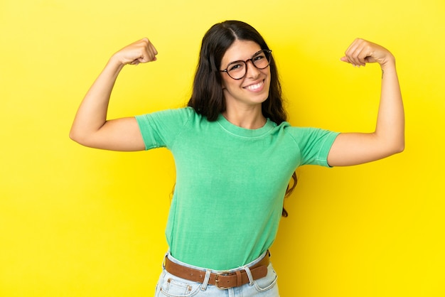 Joven mujer caucásica aislada sobre fondo amarillo haciendo gesto fuerte