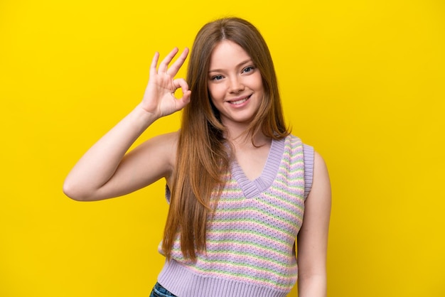 Joven mujer caucásica aislada sobre fondo amarillo mostrando signo ok con los dedos