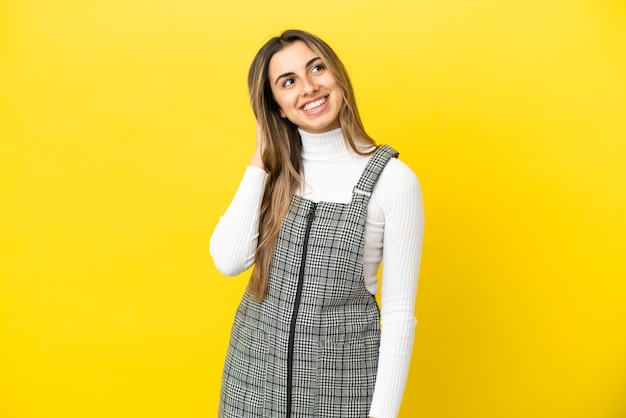 Joven mujer caucásica aislada sobre fondo amarillo pensando en una idea