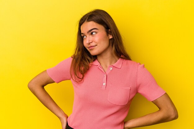 Joven mujer caucásica aislada sobre fondo amarillo soñando con lograr metas y propósitos