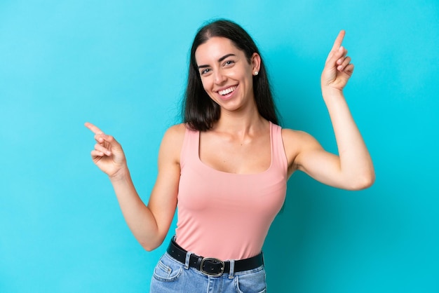 Joven mujer caucásica aislada sobre fondo azul dedo acusador a los laterales y feliz