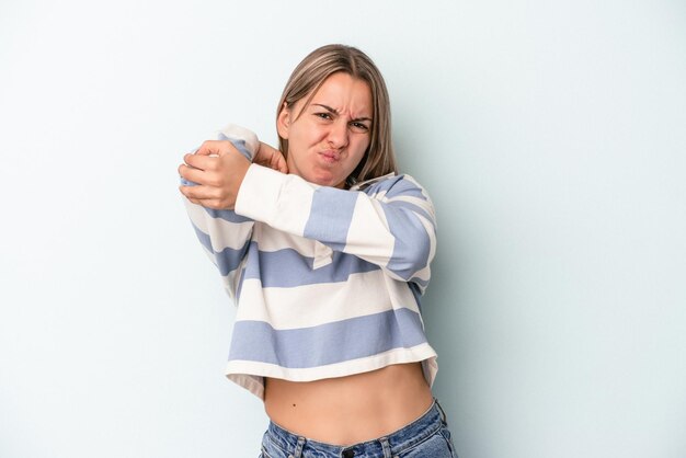 Foto joven mujer caucásica aislada sobre fondo azul con dolor de cuello debido al estrés, masajeando y tocándolo con la mano.