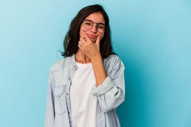 Joven mujer caucásica aislada sobre fondo azul dudando entre dos opciones.