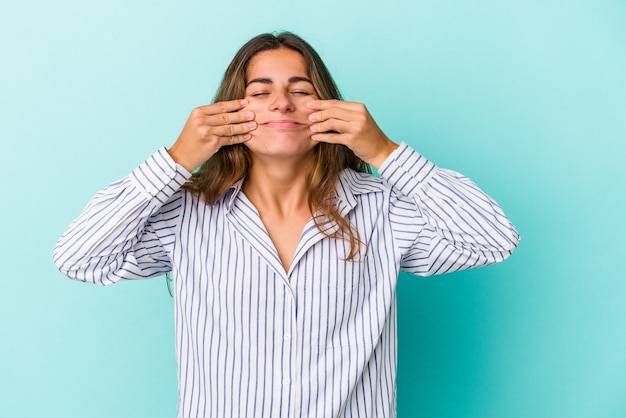 Foto joven mujer caucásica aislada sobre fondo azul dudando entre dos opciones.