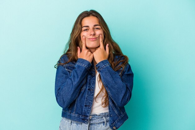 Joven mujer caucásica aislada sobre fondo azul dudando entre dos opciones.