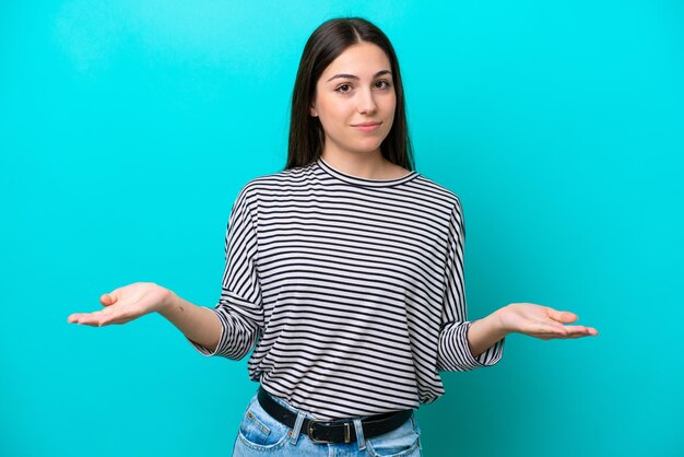 Joven mujer caucásica aislada sobre fondo azul con dudas