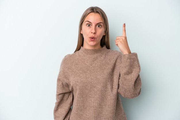 Joven mujer caucásica aislada sobre fondo azul con una gran idea, concepto de creatividad.