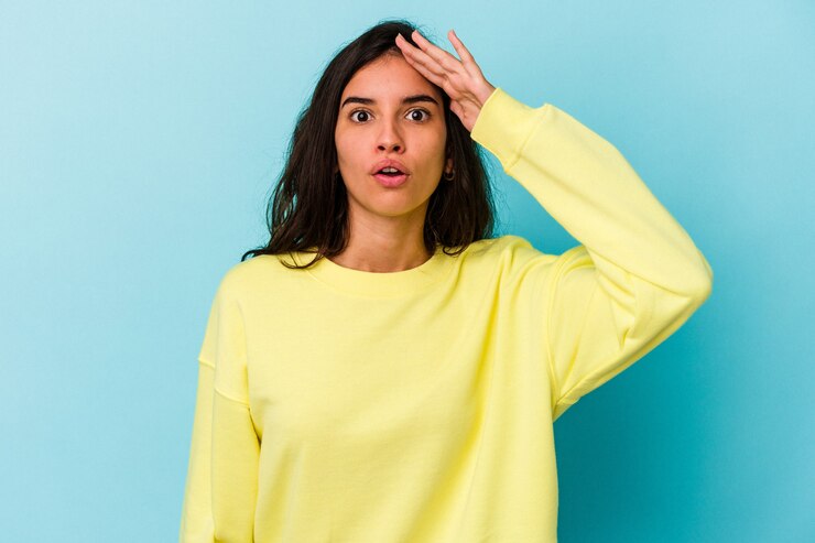 Foto joven mujer caucásica aislada sobre fondo azul grita fuerte, mantiene los ojos abiertos y las manos tensas.