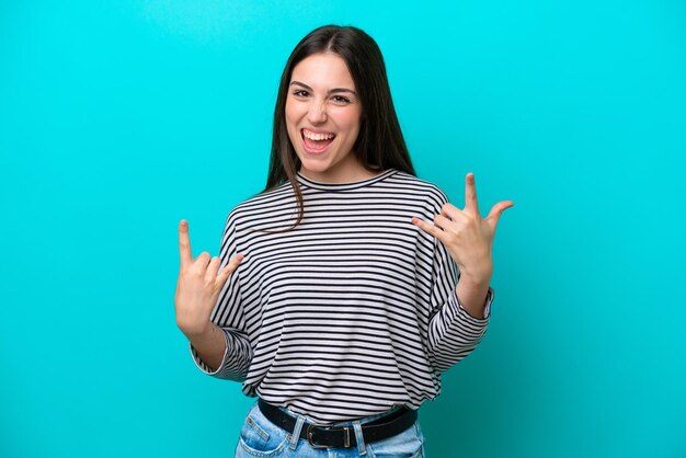 Foto joven mujer caucásica aislada sobre fondo azul haciendo gesto de cuerno