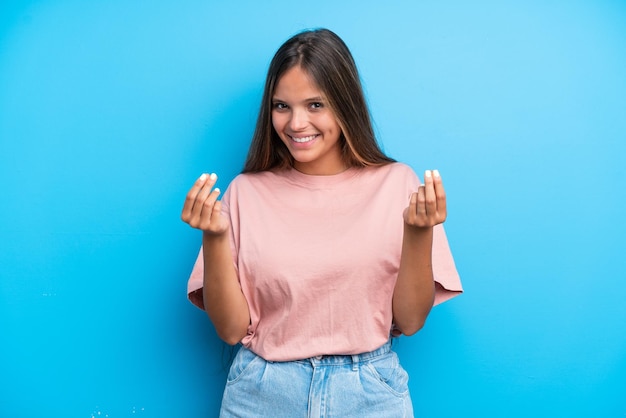 Joven mujer caucásica aislada sobre fondo azul haciendo gesto de dinero