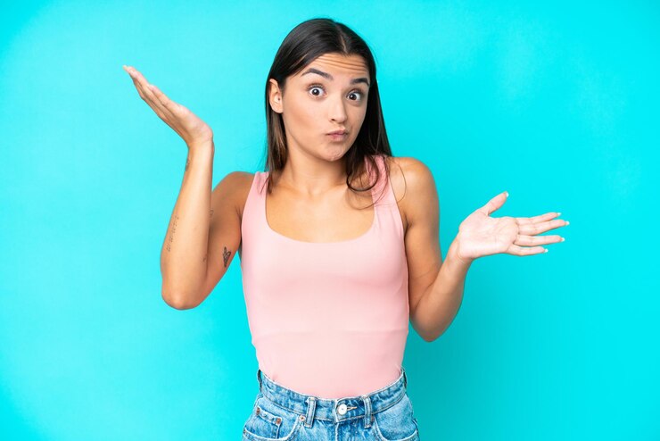 Foto joven mujer caucásica aislada sobre fondo azul haciendo gesto de dudas