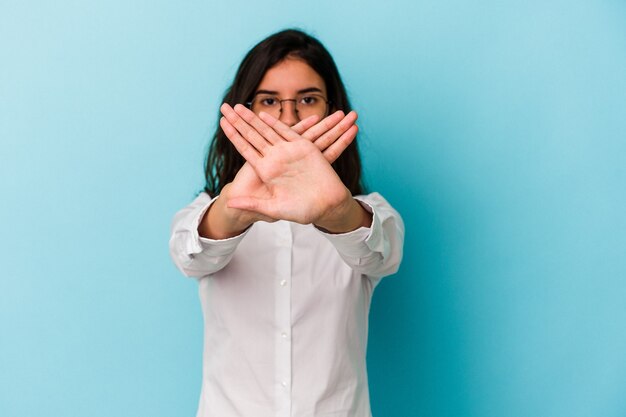 Joven mujer caucásica aislada sobre fondo azul haciendo un gesto de negación