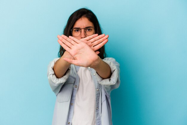 Joven mujer caucásica aislada sobre fondo azul haciendo un gesto de negación