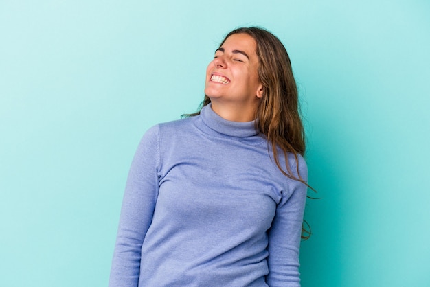 Joven mujer caucásica aislada sobre fondo azul relajado y feliz riendo, cuello estirado mostrando los dientes.