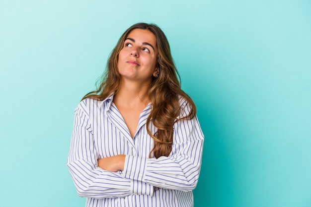 Joven mujer caucásica aislada sobre fondo azul soñando con lograr metas y propósitos