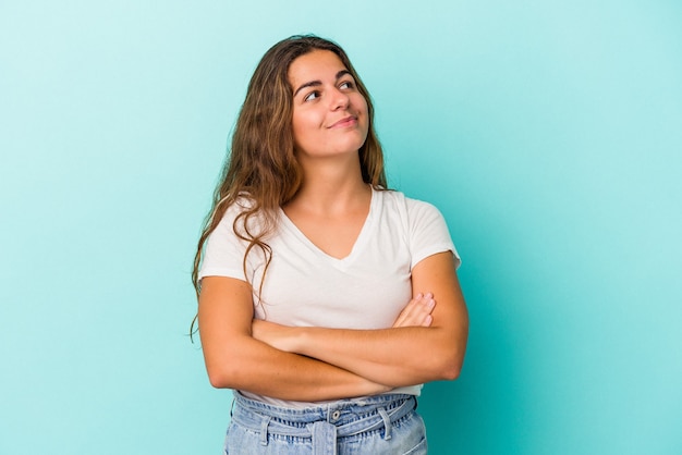 Joven mujer caucásica aislada sobre fondo azul soñando con lograr metas y propósitos