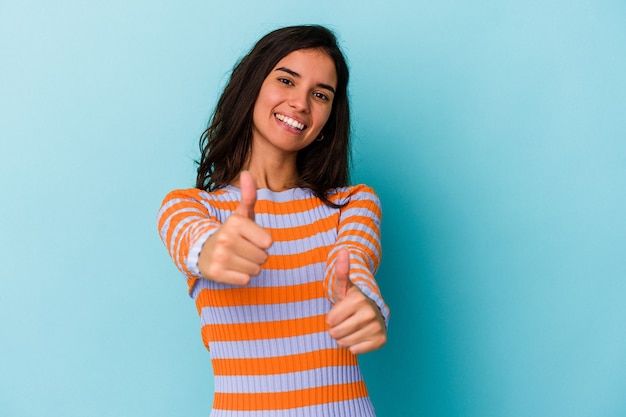 Joven mujer caucásica aislada sobre fondo azul sonriendo y levantando el pulgar