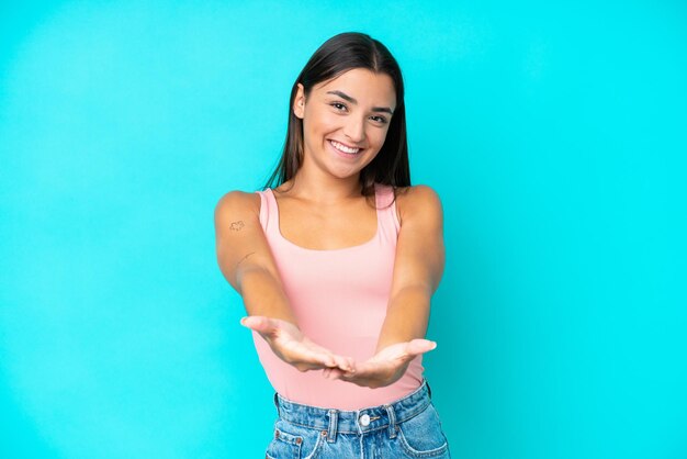 Foto joven mujer caucásica aislada sobre fondo azul sosteniendo copyspace imaginario en la palma para insertar un anuncio