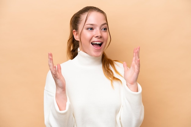 Joven mujer caucásica aislada sobre fondo beige con expresión facial sorpresa