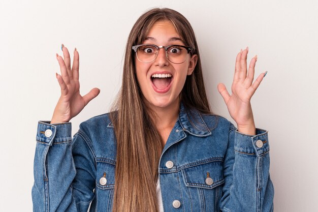 Joven mujer caucásica aislada sobre fondo blanco celebrando una victoria o un éxito, está sorprendido y consternado.