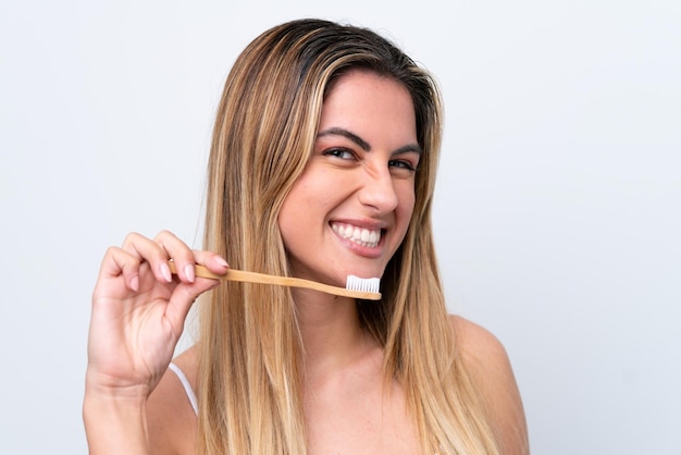 Joven mujer caucásica aislada sobre fondo blanco con un cepillo de dientes y expresión feliz