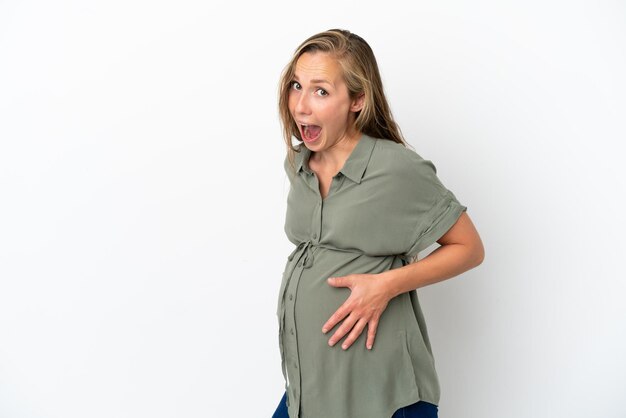 Joven mujer caucásica aislada sobre fondo blanco embarazada y haciendo gesto de sorpresa
