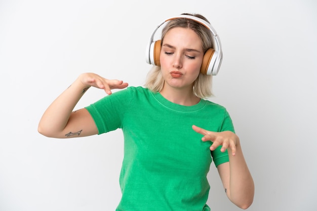 Joven mujer caucásica aislada sobre fondo blanco escuchando música y bailando