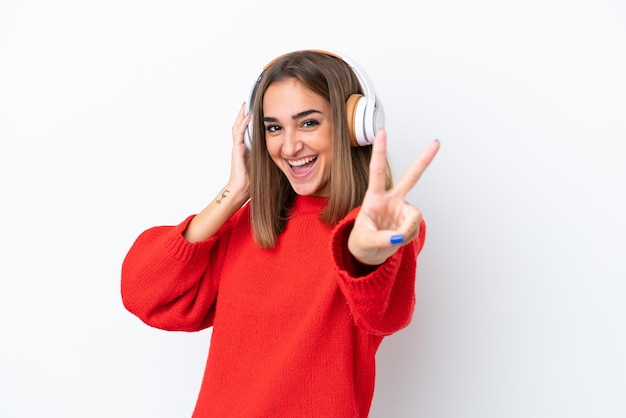 Joven mujer caucásica aislada sobre fondo blanco escuchando música y cantando