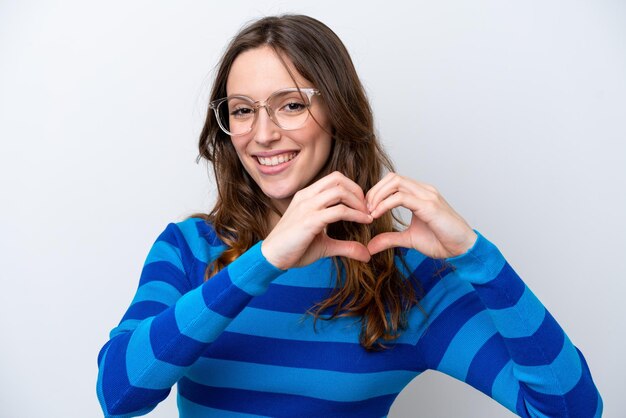 Joven mujer caucásica aislada sobre fondo blanco con gafas haciendo corazón con las manos