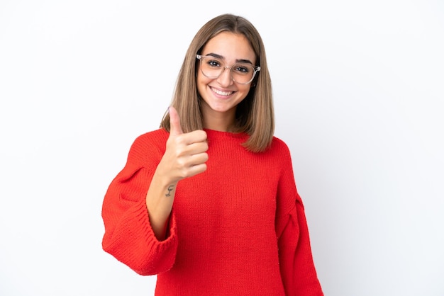 Joven mujer caucásica aislada sobre fondo blanco con gafas y con el pulgar hacia arriba