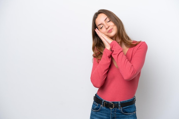 Joven mujer caucásica aislada sobre fondo blanco haciendo gesto de sueño en expresión adorable