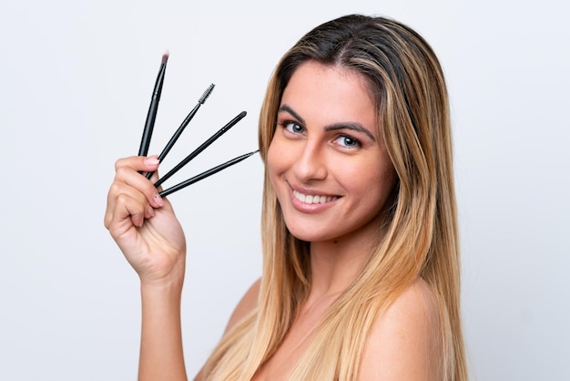 Joven mujer caucásica aislada sobre fondo blanco con pincel de maquillaje