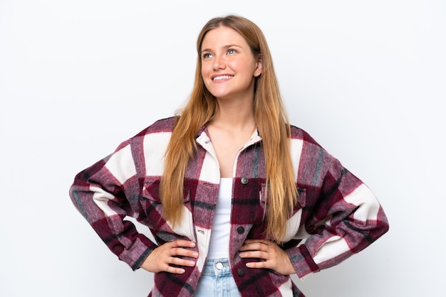 Joven mujer caucásica aislada sobre fondo blanco posando con los brazos en la cadera y sonriendo