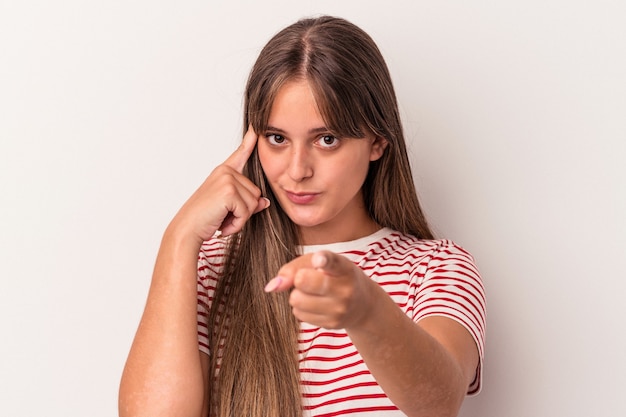 Joven mujer caucásica aislada sobre fondo blanco señalando la sien con el dedo, pensando, se centró en una tarea.